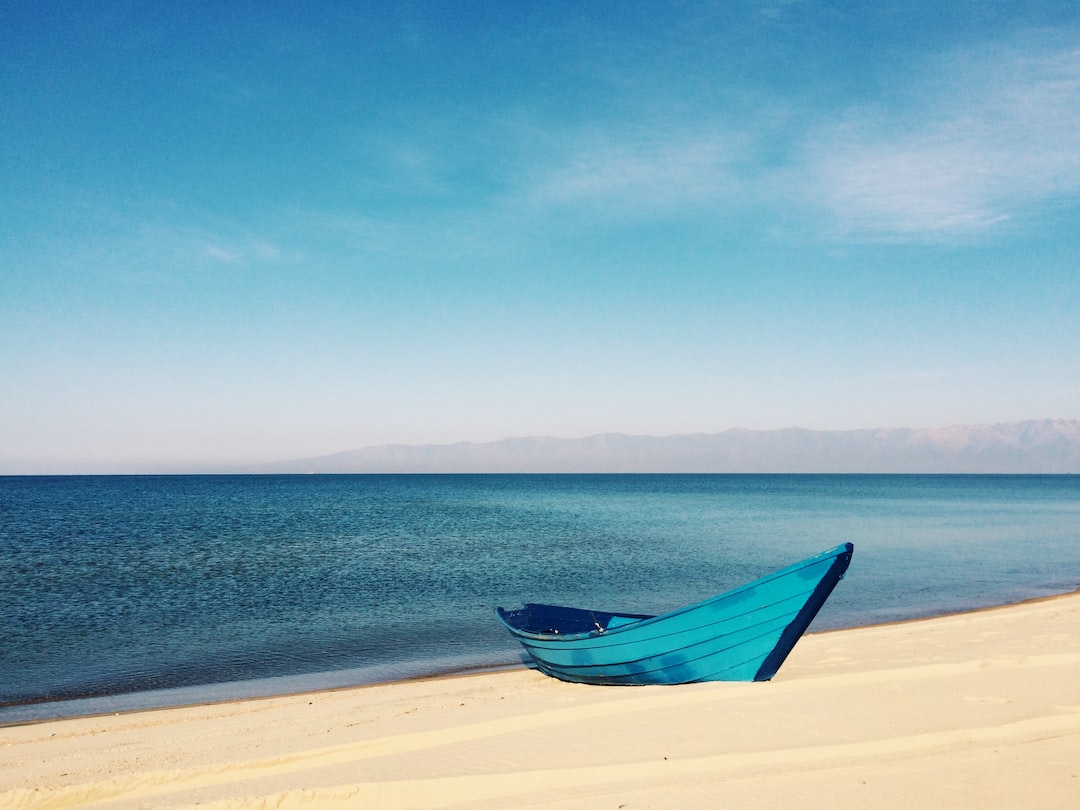 Ust-Barguzin, Republic of Buryatia, Russia by Boat Brands blue boat on sand near body of water during daytime