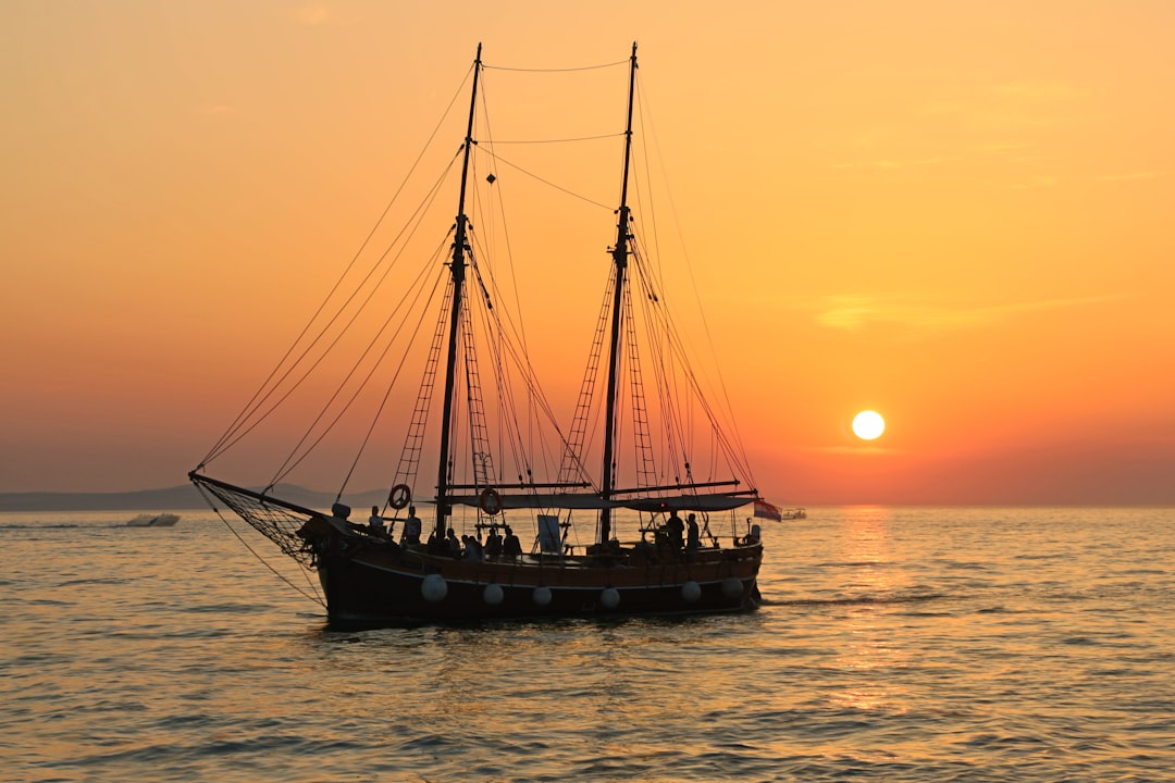 The sailboat and the sunset by Boat Brands black and white sailboat in body of water during sunset