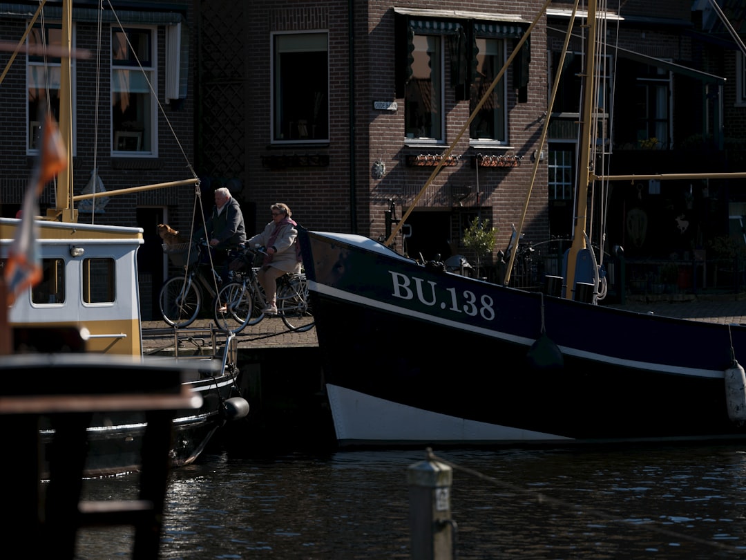 People are riding bikes by boats in a canal.